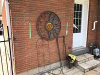 Overview of the garden decor items including sun wall hanging, trellis, metal stakes, basket stand, and wicker cone planter on the porch