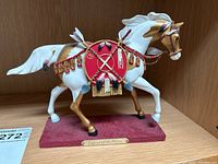 Side view of the painted ceramic horse figure with red saddle blanket and decorative elements