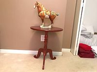 Photo showing the pottery horse figure displayed on the small wooden occasional table against a beige wall.