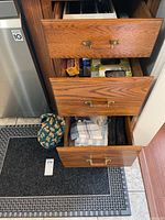 Drawers showing kitchen linens and bags, kitchen mat and cloth bag holder on floor