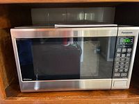 Full front view of Panasonic Inverter microwave NN-ST6635 placed in wooden shelf.