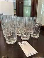 Nine Pinwheel crystal highball glasses arranged on a table, showing three taller glasses in front and six shorter behind.