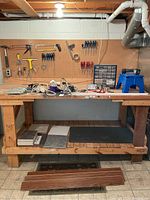 Overall lot with pegboard of tools, hardware caddy, cords, tiles and flooring at basement workbench