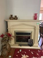 Full frontal view of the Valor electric fireplace insert with faux stone mantle. Decorative vases placed around not included, remotes and manual positioned at hearth.