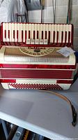 Front view of red Cellini accordion showing keyboard, grille, and strap