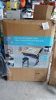 Photo of the box showing the Artist's Loft branding and product name 'Arts & Crafts Creative Table'. Box has image showing assembled table and included stool.