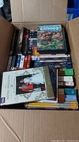 Box filled with multiple DVDs including The Croods, Royal Wedding, and others stacked with visible colorful covers.