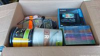Box with Garmin Nuvi 2595 in original box, Sony MP3 player, DVDs, plastic containers, and cables.