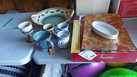 Full lot view of four pottery mugs, one goblet, glass serving tray, Crabtree & Evelyn dish, Sarah Peyton Home frosted glass sectional tray and large bowl on table
