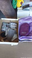 Box containing various travel accessories including earphones, comfort set, locks with keys, and chargers.
