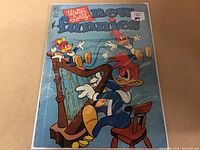 Front cover of the 1952 Woody Woodpecker #184 comic book showing Woody Woodpecker and two other birds around a harp. The comic is inside a protective plastic sleeve with visible light reflection.