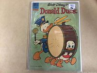 Photo of 1962 Walt Disney's Donald Duck Comic #83, showing front cover with Donald Duck in a marching band outfit and a drum with one of his nephews behind it. The comic is in a protective plastic cover.