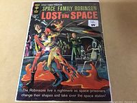 Front cover of Lost in Space #16 comic book in protective plastic sleeve showing colorful retro artwork and title.