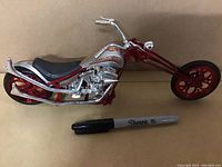 Side view of the 4th Chopper replica motorcycle showing metallic red and silver color scheme, black seat, flame decals, and detailed engine and exhaust parts.