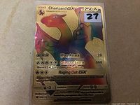 Holographic Charizard GX Pokémon card with golden and red foil, showing attacks and energy requirements, in protective sleeve.