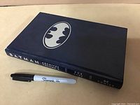 Closed hardcover book with Batman logo and title on spine.
