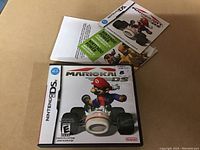 Front cover of Mario Kart DS case with Mario on kart and paperwork on top