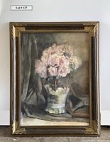 Full view of framed floral still life painting showing flower bouquet in vase with fabric and dark background.