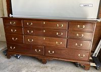 Front view of the eleven-drawer cherry wood dresser showing brass bail handles and keyhole plates.