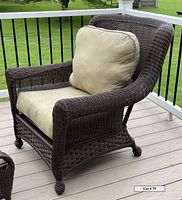 Side angle showing the full chair structure, armrests, woven resin texture, and off-white cushion with visible dirt marks on the seat.