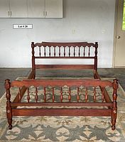 Full view of the spindle bed frame showing the turned spindle footboard and solid wood construction.
