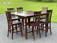 Dark wood pub-height table surrounded by six matching chairs, shown outdoors on pavement with grassy background. The table has a square top and the leaf is installed, making the table larger.