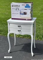 Kenmore sewing machine box on top of creamy white sewing table with two drawers and curved legs.