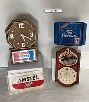 Four vintage bar decor items grouped on white surface: Pepsi clock, Stroh's clock, Amstel Light sign, Old Vienna tray