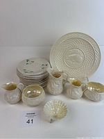 Front view showing all 17 items including 12 harp side plates with embossed shamrocks, Christmas plate, two cream and sugar sets, milk jug, and small shell-shaped Salter piece.