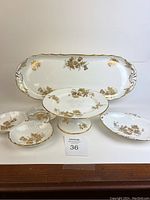 Full lot image showing large tray, cake stand, triple dish, and candy dish with gold floral patterns on white bone china