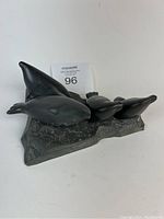 Side view showing the four smooth seal sculptures placed on a textured stone rock base. Some seals are resting on the base without full support due to missing dowels.