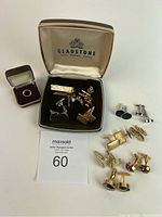 Wide shot showing all cuff links, tie clips, ring, and boxes, with Gladstone logo inside box lid