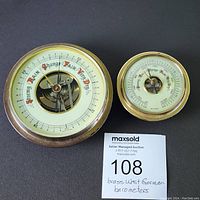 Top view of both brass barometers showing faces and dial markings.