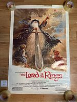 Full front view of the Gandalf and hobbits illustrated poster with tape on corners and visible wear around edges.