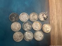 Top view of 11 Canadian silver 10 cent coins arranged on a blue surface showing obverse with monarch portraits.