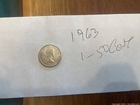 1963 Canadian 50 cent coin placed on white paper with handwritten note '1963 1-50 Cent'