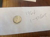 Photo of the obverse side of the 1964 Canadian 50 cent silver coin on white paper with text.