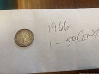Front side of the 1966 Canadian 50 cent silver coin placed on a piece of paper with handwritten text.