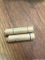 Two rolls of Canadian pennies on a wooden surface, one labeled 1932 and the other labeled 1944.