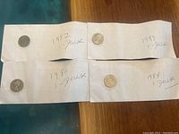 Four Canadian 1 dollar coins placed on papers labeled 1980, 1982, 1983, and 1984.