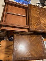 Photo showing the patterned wood tabletops of the foldable coffee tables with a starburst wood grain design and one table in folded position showing metal support bars.