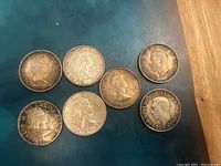 Front view displaying the obverse side of 7 Canadian silver half dollar coins with different portrait styles.