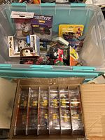 Overview of action figures and collectibles in a storage bin, showing Funko Pop, Dorbz, and other toy packages