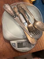 Photo of four sterling silver items on a digital scale weighing 129 grams total.