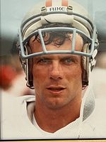 Close-up view of Joe Montana wearing a white football helmet labeled 'BIKE' and white jersey, showing facial details and helmet faceguard.