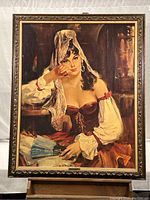 Full view of the framed large embossed artboard print depicting a woman in vintage attire holding a blue fan.