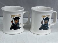 Photo showing two white ceramic coffee mugs side by side, both featuring the Rush Limbaugh caricature in patriot attire with the text 'TWO IF BY TEA'.