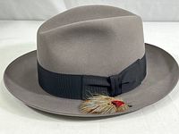 Exterior front angle view of gray felt fedora with black ribbon and feather
