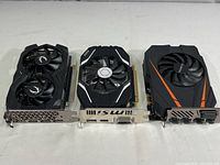 Three graphics cards side by side showing front fan cooling designs and PCIe connectors