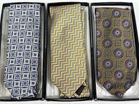 Three vintage men's neckties in boxes, left to right: JZ Richards with geometric blue-gray squares, Ermenegildo Zegna yellow-purple zigzag, Robert Talbot circular medallions in gold and purple